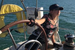 Woman steering a monohull sailboat