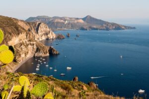 Looking down from cliffs at boats at anchor in cove of Sicily's Vulcano Island, with cactus in foreground