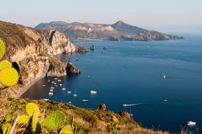 Looking down from cliffs at boats at anchor in cove of Sicily's Vulcano Island, with cactus in foreground
