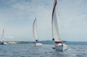 A catamaran and two monohull sailboats under sail in Croatia