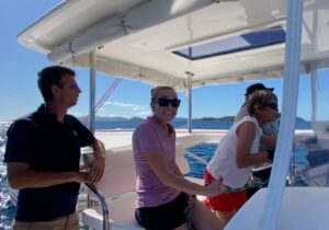 Male sailing instructor and two women on a catamaran yacht