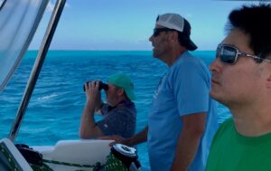 Three men looking at horizon on a sailboat