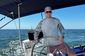 Man steering a big sailboat