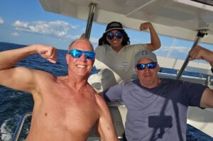 2 men and a woman looking happy on a big sailboat