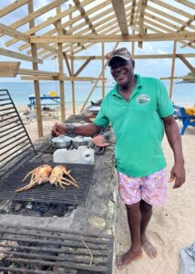 Caribbean islander cooking lobster on outside grill