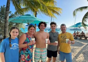 Family on beach with sailboats behind