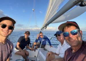Offshore Sailing instructor in blue with four Learn to Sail students