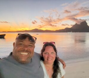 Two people taking selfie on beach with sunset