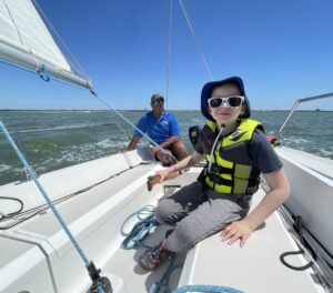 Young boy steering a boat with instructor in background